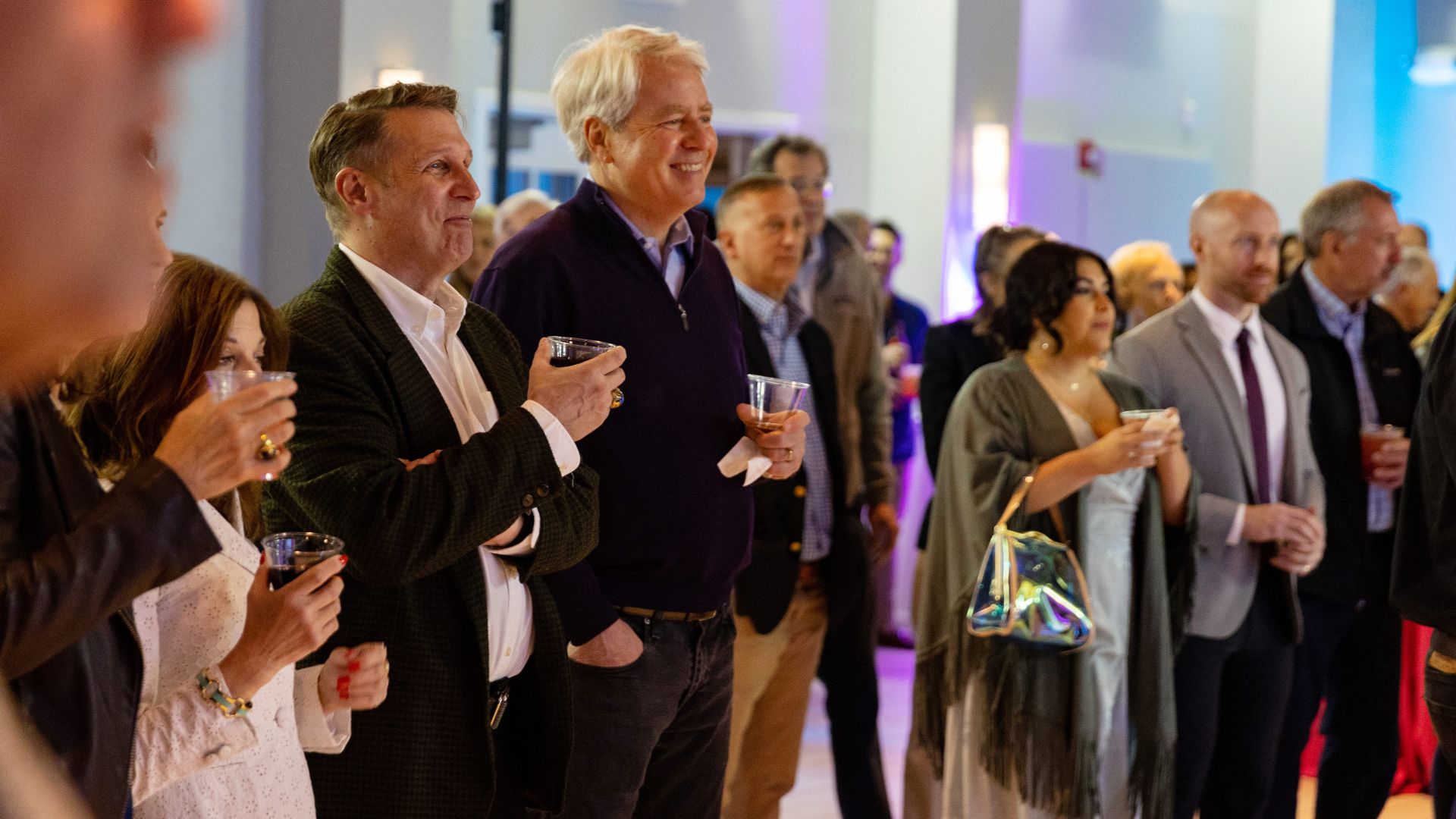 A group of people smiling and holding drinks at an event.