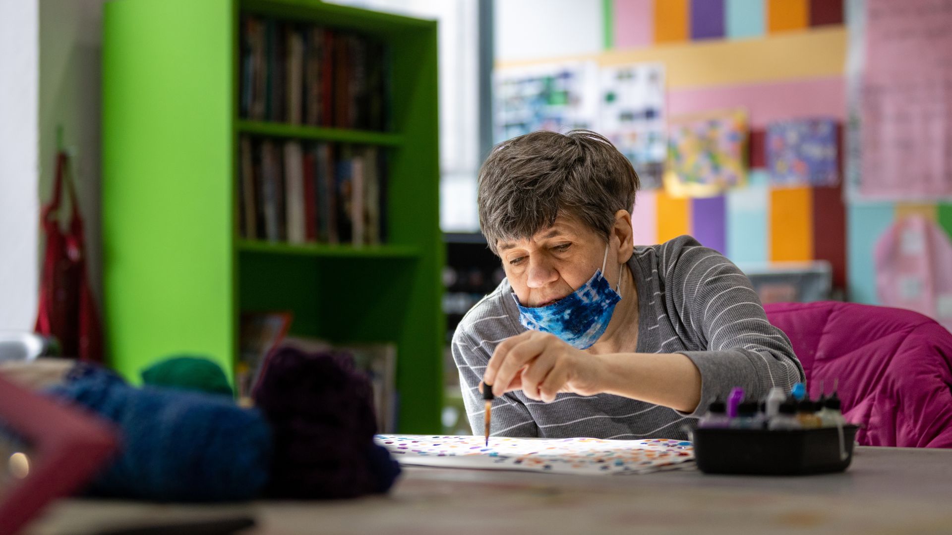A woman making a painting with a dropper tool, seen from a right angle.