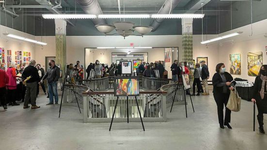 People walking around an art exhibit featuring TKC's 2022 'A Unique Perspective' Calendar.